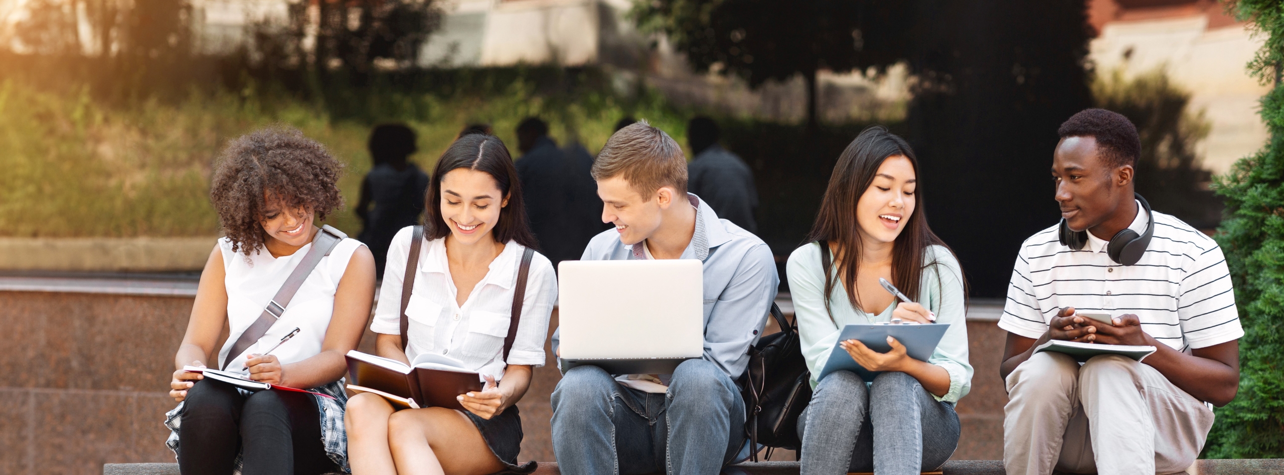 Group of happy teen high school students studying outdoors